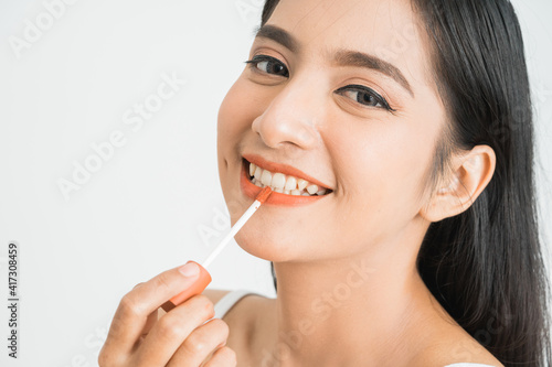 beauty face of asian woman. portrait of female applying lipstick on her face close up