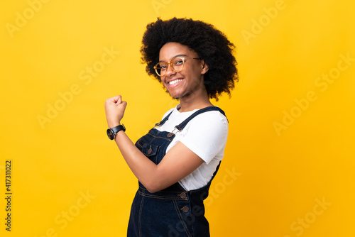 Young African American woman isolated on yellow background celebrating a victory