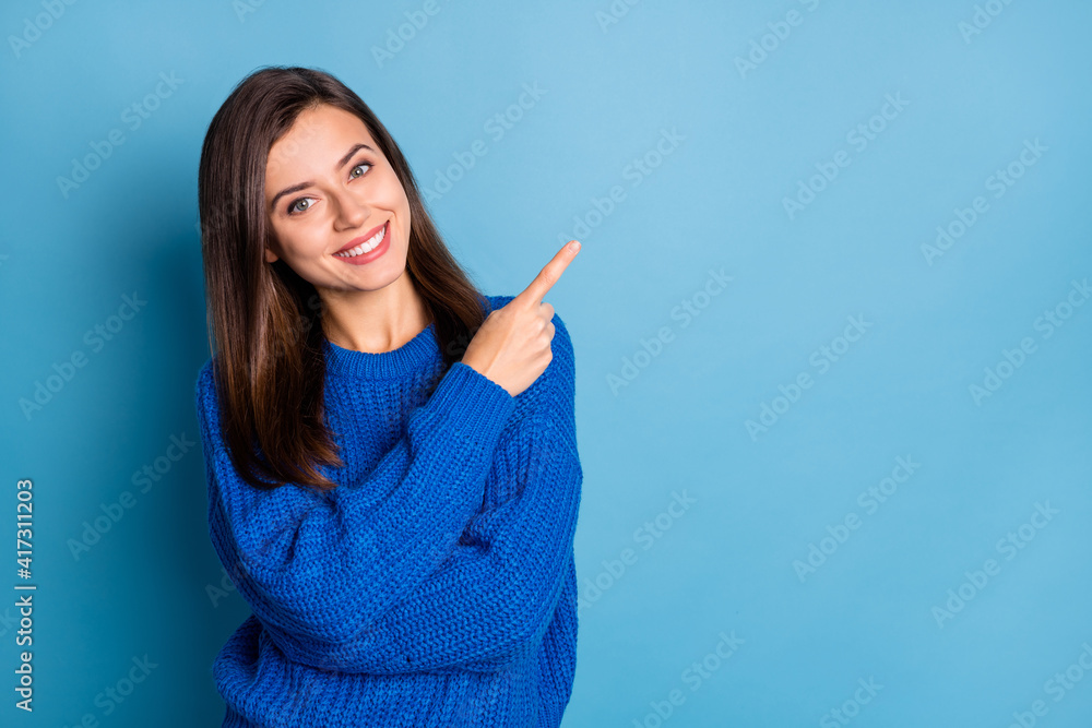 Photo of young beautiful smiling good mood positive girl pointing finger in copyspace isolated on blue color background Photo of young beautiful smiling good mood positive girl pointing finger in copyspace isolated on blue color background