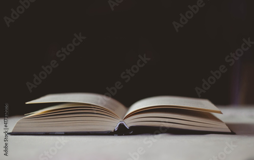 Open book lying on a table with a white tablecloth on a black background. 
