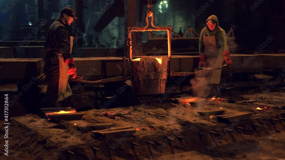 Workers pour hot metal into molds.Industrial worker casting metal at metallurgical factory. Molding molten metal at industrial plant. Manufacturing iron products in heavy industry.Video 4 k. Workers pour hot metal into molds.Industrial worker casting metal at metallurgical factory. Molding molten metal at industrial plant. Manufacturing iron products in heavy industry.Video 4 k.