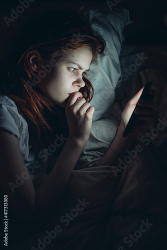 woman before bed with a phone in her hands addiction reading news
