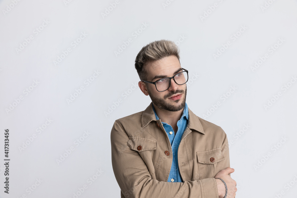 clever young casual guy looking to side and holding arm in fashion pose clever young casual guy looking to side and holding arm in fashion pose