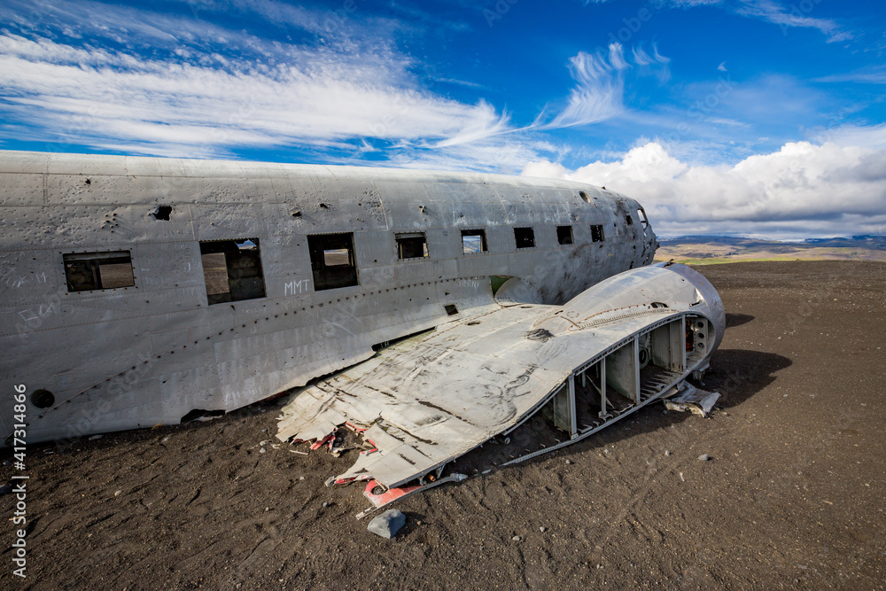 The famous tourist attraction site near Solheimasandur abandoned plane wreck place with black sand, desert sunny day with white clouds landscape in Southern Iceland, travel photo