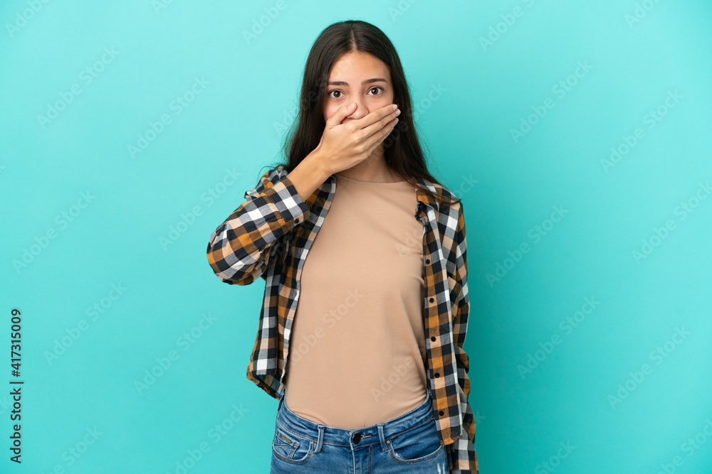 Young French woman isolated on blue background covering mouth with hand Young French woman isolated on blue background covering mouth with hand