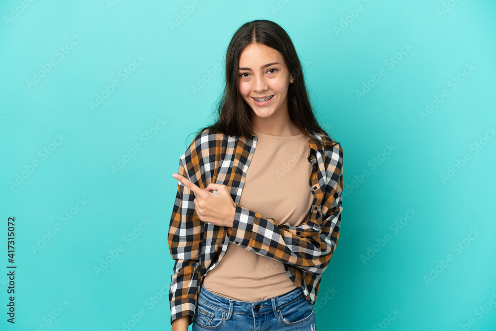 Young French woman isolated on blue background pointing to the side to present a product Young French woman isolated on blue background pointing to the side to present a product