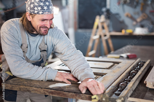 Male carpenter working on old wood in a retro vintage workshop.
