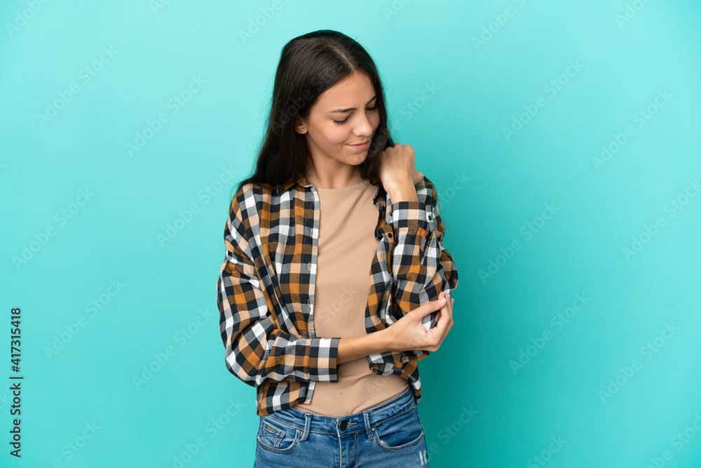 Young French woman isolated on blue background with pain in elbow Young French woman isolated on blue background with pain in elbow