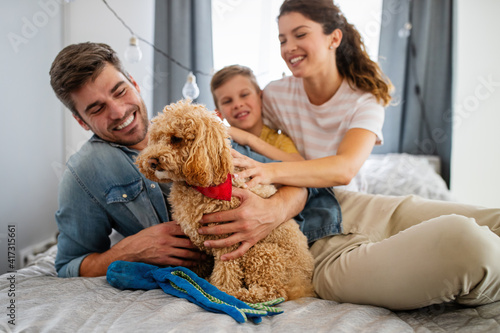 Happy young friendly family spending fun times together and cuddling with their pet at home