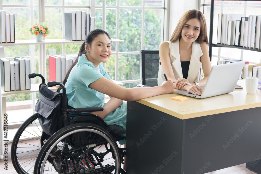 Young disabled Asian businesswoman working together with her colleague in office workplace Young disabled Asian businesswoman working together with her colleague in office workplace
