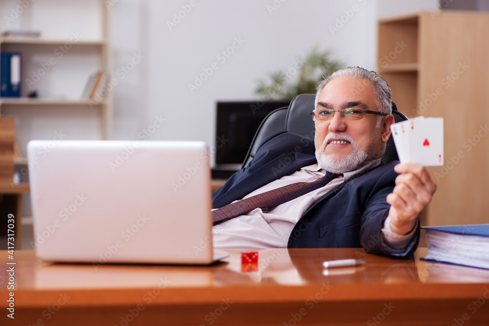 Old male employee playing cards at workplace Old male employee playing cards at workplace