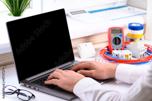 . Electrical installation courses. On the table there is a computer, cable, tester, automatic switch. Online learning