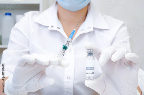 COVID-19 vaccine in researcher hands, female doctor holds syringe and bottle with vaccine for coronavirus cure.