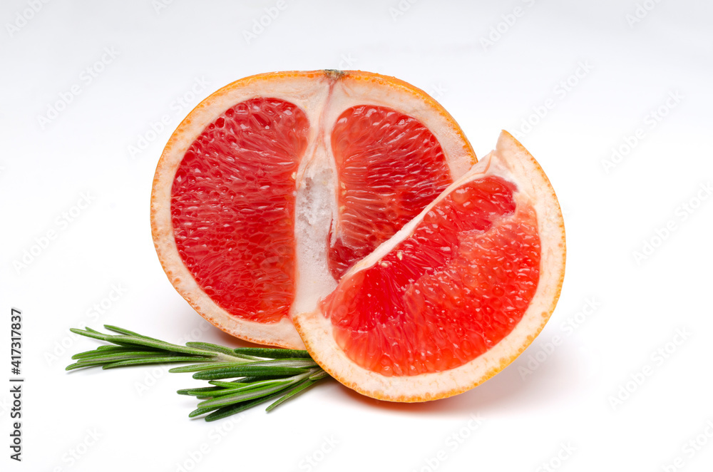 Closeup of half of juicy grapefruit and slice of one, rosemary on the white surface