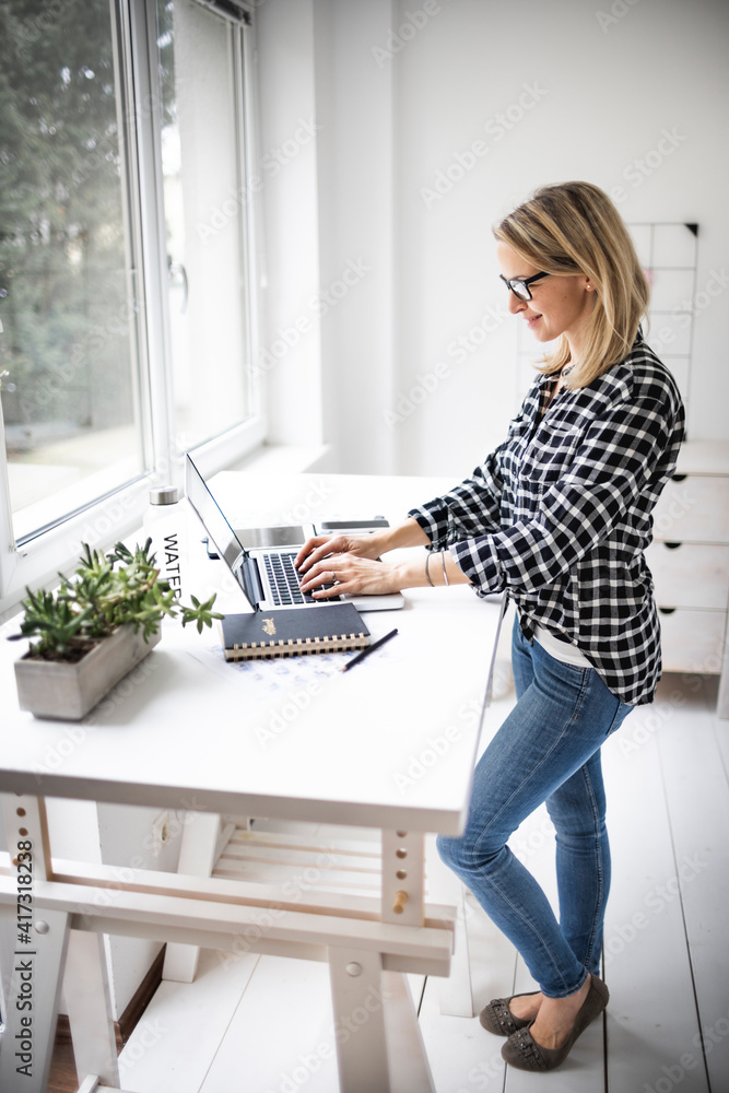Businesswoman working at a standing desk in a modern office space Businesswoman working at a standing desk in a modern office space