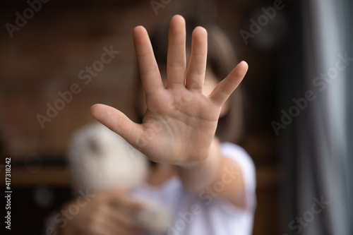 Crop close up of little girl child stretch hand show no gesture protest against domestic violence. Small teen child stand against discrimination or school abuse. Childhood problem, voice concept. photo