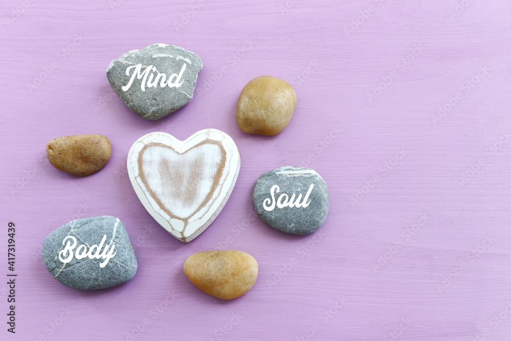 Obraz premium zen stones with the words Mind body soul. purple wooden background