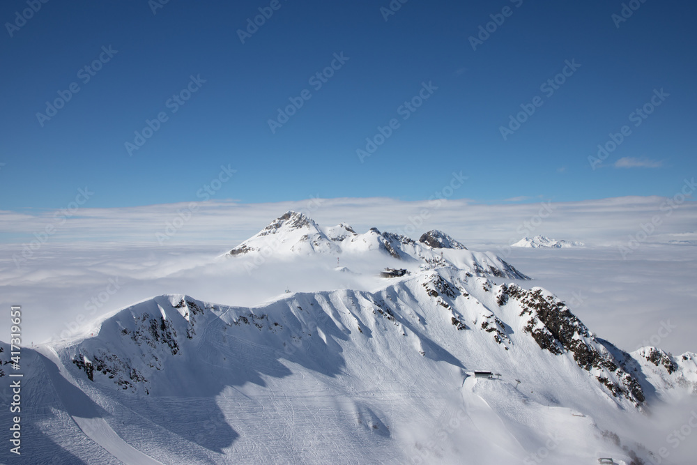 Snow peaks over clouds. Caucasus rocks. White mountains and blue sky. Snow peaks over clouds. Caucasus rocks. White mountains and blue sky.