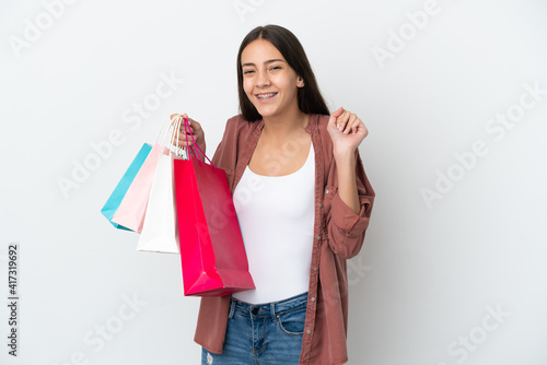 Young French girl isolated on white background holding shopping bags and smiling