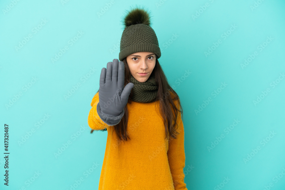 Young French girl isolated on blue background with winter hat making stop gesture Young French girl isolated on blue background with winter hat making stop gesture