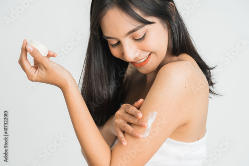 Young skin care asian woman applying body lotion on arm and shoulder