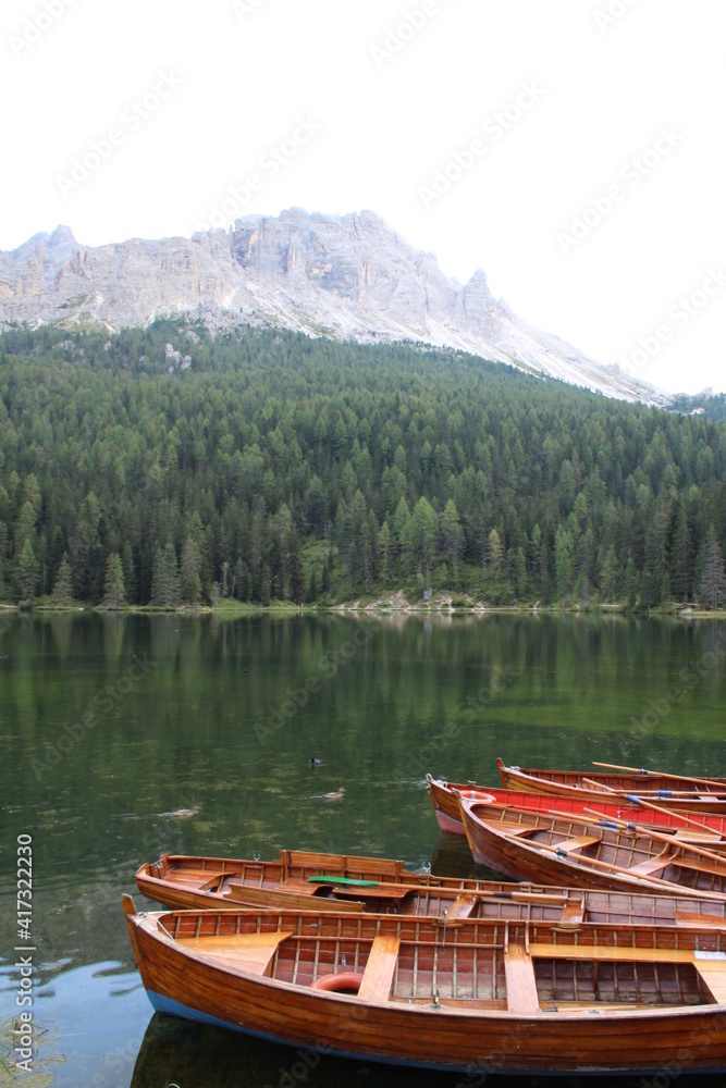 Holzruderboote auf einem See mit Bergen und Bäumen im Hintergrund 