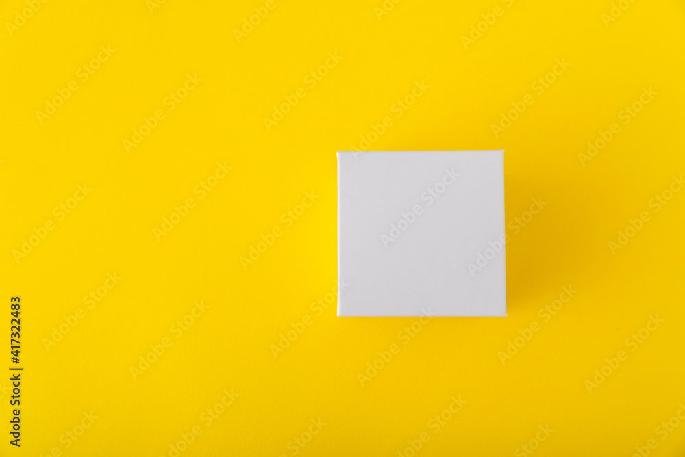 White square cardboard box on yellow background. Copy space. Mock up. White square cardboard box on yellow background. Copy space. Mock up.