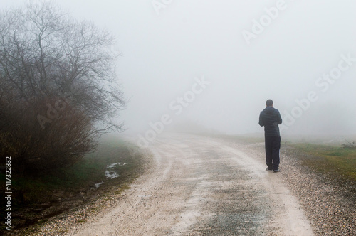 Persona, un hombre en un camino en la naturaleza, en el campo, un dia con mucha niebla.