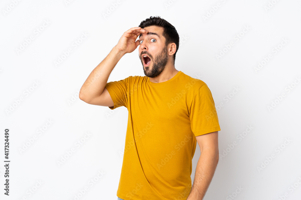 Young handsome man with beard isolated on white background doing surprise gesture while looking to the side Young handsome man with beard isolated on white background doing surprise gesture while looking to the side