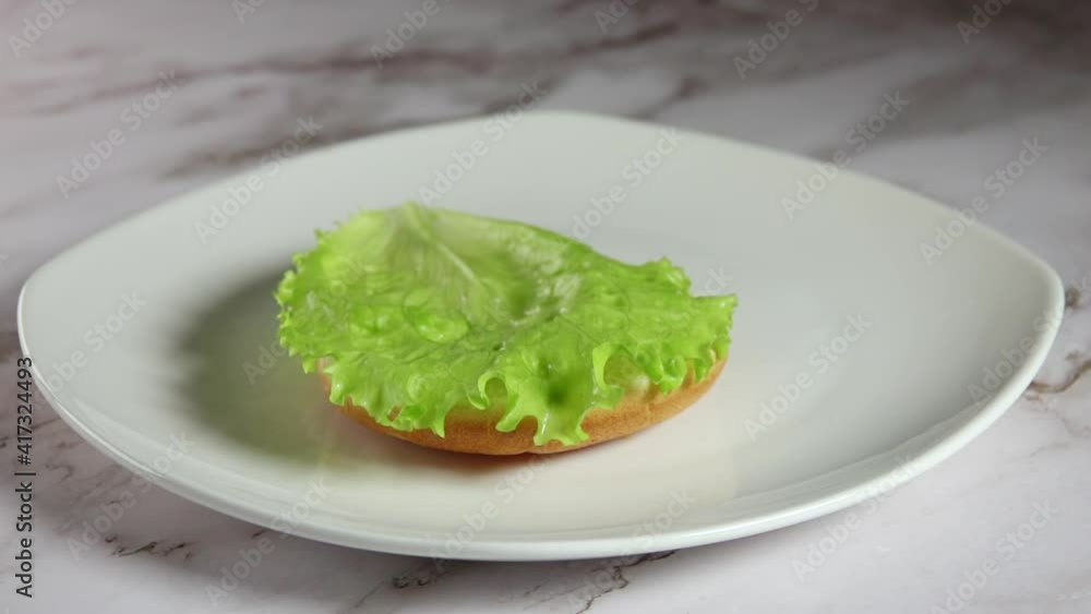 Fresh Lettuce Falls on Burger Bun (1 of 4). Slow Motion Fresh Lettuce Falls on Burger Bun (1 of 4). Slow Motion