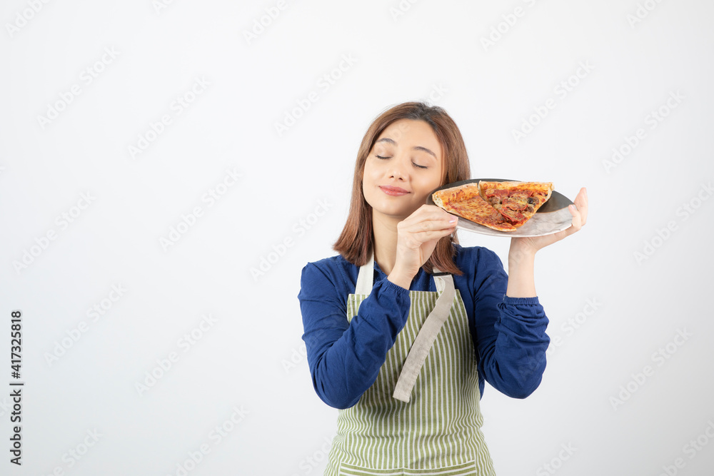 Portrait of woman in kitchen apron holding plate of pizza on white background Portrait of woman in kitchen apron holding plate of pizza on white background