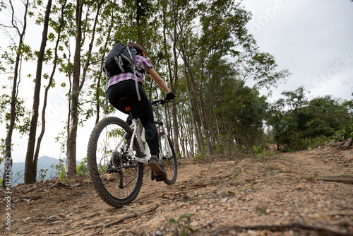 Woman cyclist cycling on mountain top forest trail