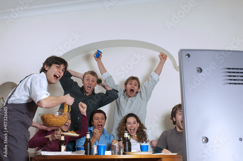 Un gruppo di amici si divertono cenando e guardando la partita a casa photo