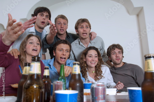 Un gruppo di sette amici seduti al tavolo con le birre mentre guardano la partita di calcio