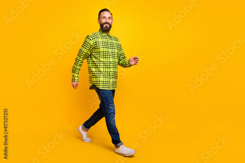 Full length profile side photo of mature man happy positive smile go walk wear casual outfit isolated over yellow color background