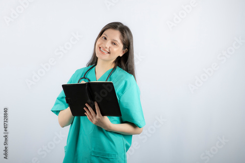 Photo of a young female doctor standing with notebook and pencil
