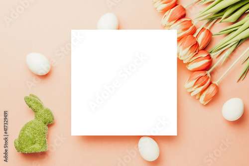 Easter eggs isolated. Golden, white colour egg in basket with spring tulips, white feathers on pastel pink background in Happy Easter decoration. Flat lay, top view.