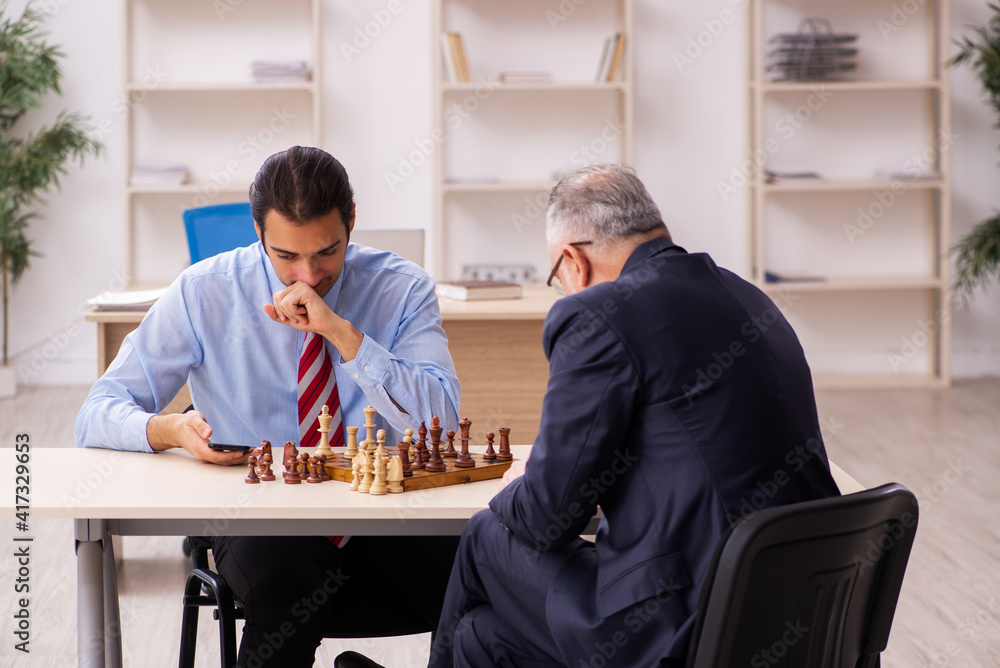 Two businessmen playing chess in the office Two businessmen playing chess in the office