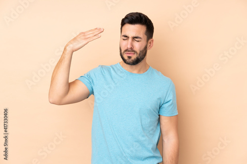 Caucasian handsome man isolated on beige background with tired and sick expression