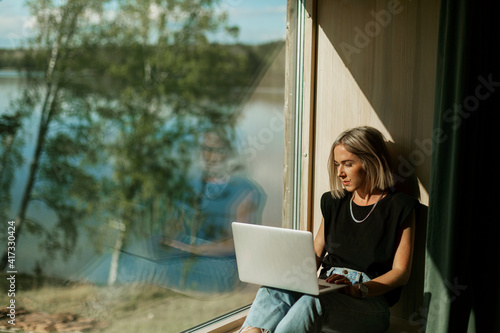 Woman using laptop near window photo