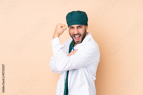 Surgeon man isolated on beige background making strong gesture