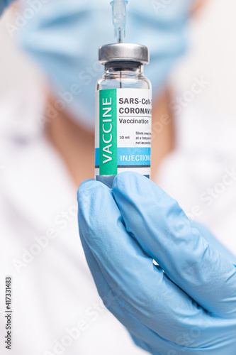 SARS - CoV2 Vaccination concept. Close up COVID-19 vaccine dose. A doctor or nurse in a laboratory holds a vial with a vaccine. Pandemic immunity