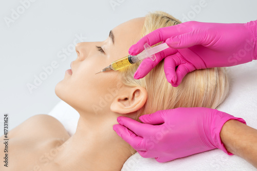 Cosmetologist does prp therapy on the face of a beautiful woman in a beauty salon. Cosmetology and professional skin care.