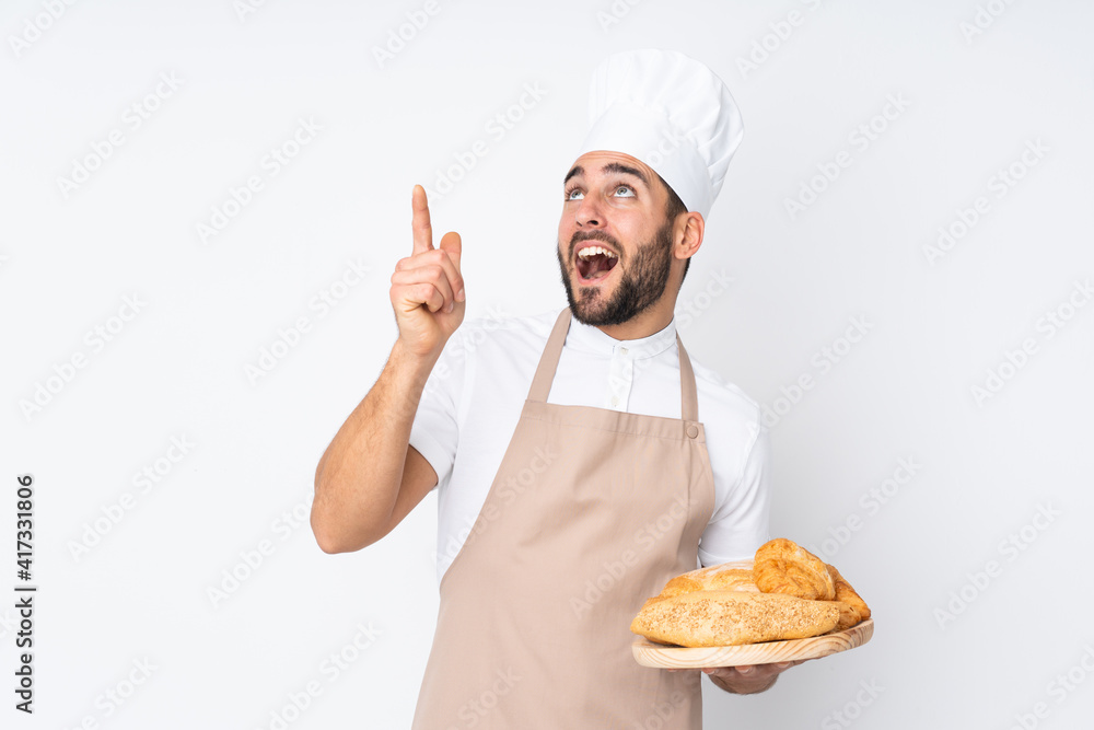 Male baker holding a table with several breads isolated on white background pointing with the index finger a great idea Male baker holding a table with several breads isolated on white background pointing with the index finger a great idea