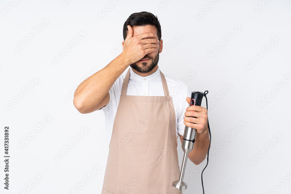 Man using hand blender isolated on white background covering eyes by hands Man using hand blender isolated on white background covering eyes by hands
