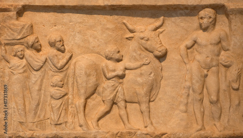 Votive relief Panis Aigirios to Heracles, form of a naiskos, from the sanctuary of Heracles at Kynosarges in Athens, Greece. Heracles is depicted at the right holding the lions pelt. 4th century B.C.