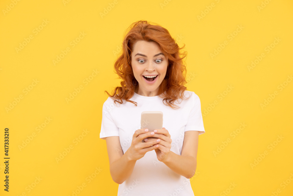 surprised woman chatting in smartphone or make online shopping on yellow background, emotions. surprised woman chatting in smartphone or make online shopping on yellow background, emotions.