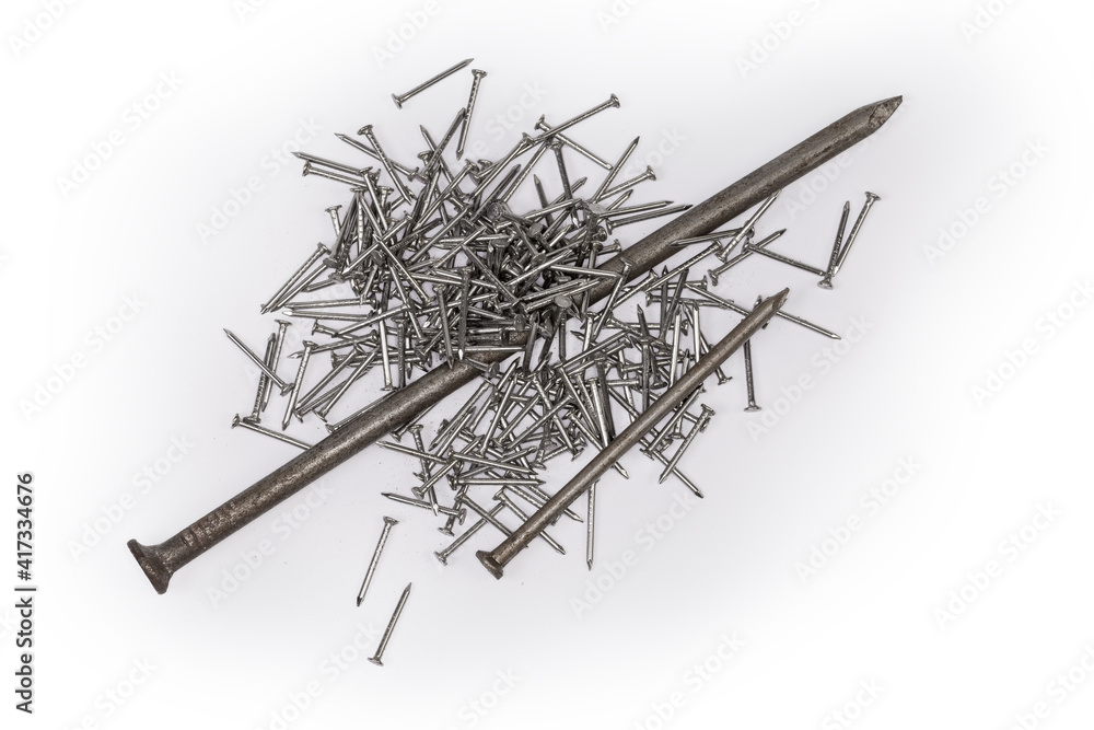 Big and medium nails, pile of small nails on white surface Big and medium nails, pile of small nails on white surface