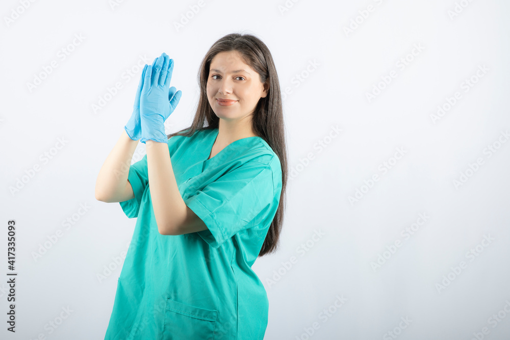 Female doctor in medical gloves showing hands on white background Female doctor in medical gloves showing hands on white background