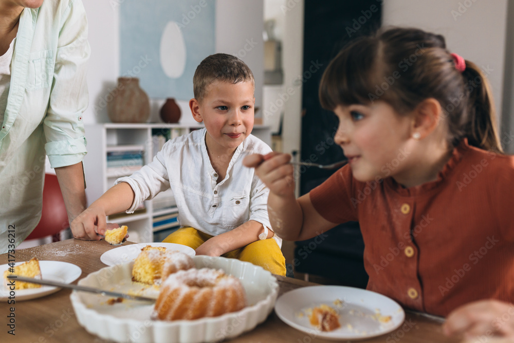 mother and her children enjoying time together. they eating cake at home mother and her children enjoying time together. they eating cake at home